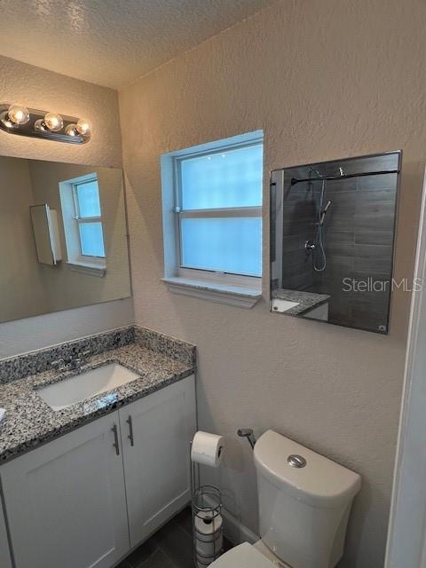 1620 Hialeah St, Orlando, FL 32808 - bathroom featuring vanity, a textured wall, toilet, and a textured ceiling