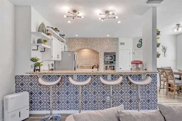 9455 Belmont Ter, Oviedo, FL 32765 - kitchen with stainless steel appliances, open shelves, wood finished floors, open floor plan, and white cabinetry