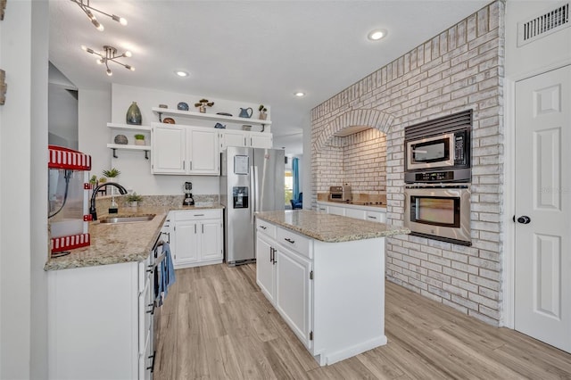 9455 Belmont Ter, Oviedo, FL 32765 - kitchen featuring stainless steel appliances, open shelves, a sink, white cabinets, and light wood-style flooring