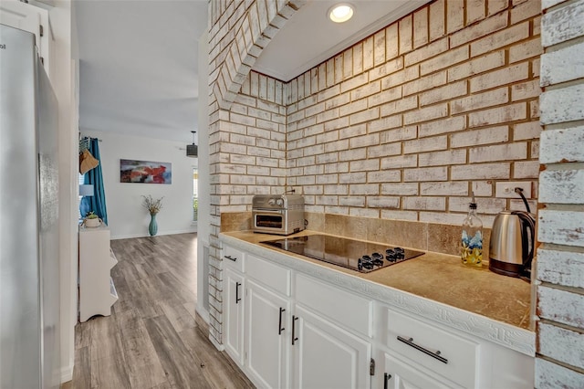 9455 Belmont Ter, Oviedo, FL 32765 - kitchen featuring black electric stovetop, white cabinetry, baseboards, light wood-style floors, and decorative backsplash