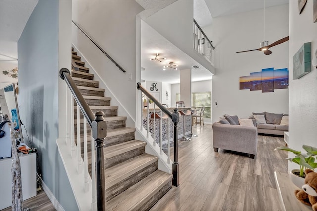 9455 Belmont Ter, Oviedo, FL 32765 - stairway featuring ceiling fan, wood finished floors, and a high ceiling