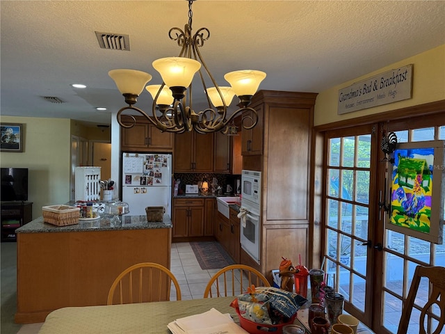 11314 Huggins St, Leesburg, FL 34788 - kitchen featuring white appliances, backsplash, a chandelier, a center island, and a textured ceiling