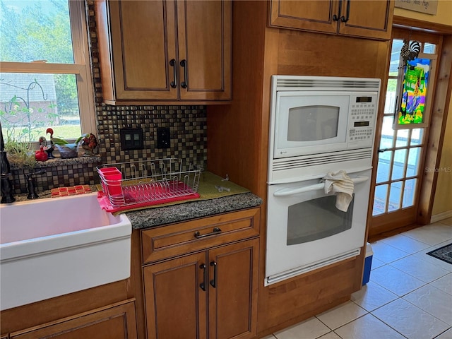 11314 Huggins St, Leesburg, FL 34788 - kitchen featuring white appliances, brown cabinetry, tasteful backsplash, and light tile patterned flooring