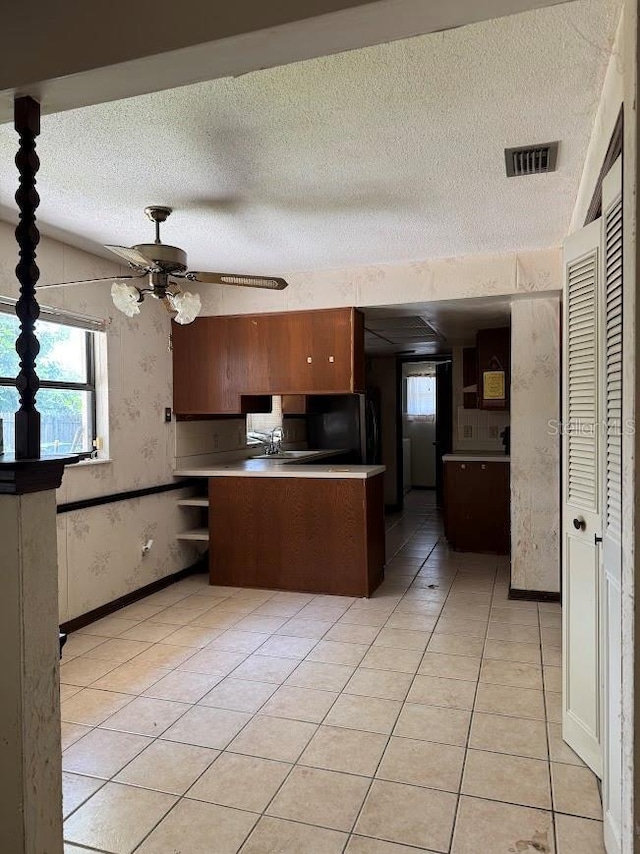 6616 Blanche Ct, Orlando, FL 32818 - kitchen featuring a textured ceiling, a sink, a ceiling fan, light tile patterned floors, and a peninsula