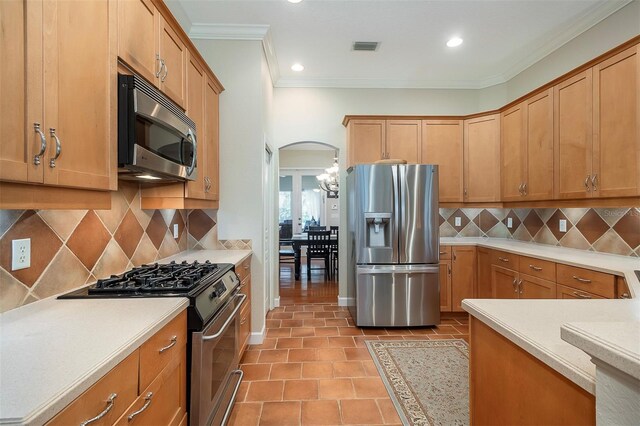 8335 Lake Burden Cir, Windermere, FL 34786 - kitchen with stainless steel appliances, arched walkways, light countertops, crown molding, and light tile patterned floors