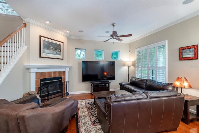 8335 Lake Burden Cir, Windermere, FL 34786 - living area featuring light wood finished floors, ceiling fan, stairs, a tiled fireplace, and ornamental molding