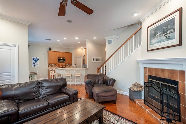 8335 Lake Burden Cir, Windermere, FL 34786 - living area featuring a ceiling fan, light wood finished floors, stairs, ornamental molding, and a tiled fireplace