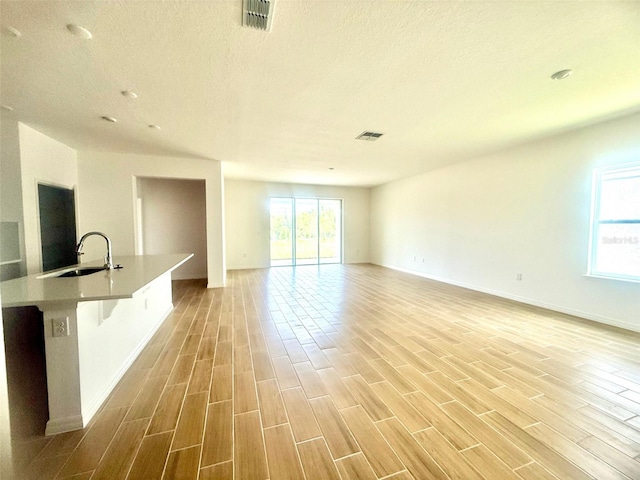 131 Addle Hill Ct, Deland, FL 32720 - unfurnished living room with a sink, light wood finished floors, baseboards, and a textured ceiling