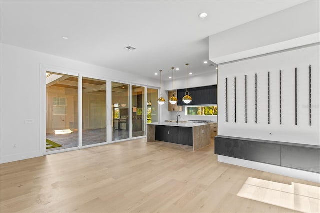 7706 Ficquette Rd, Windermere, FL 34786 - kitchen with light countertops, an island with sink, light wood-style flooring, recessed lighting, and decorative light fixtures