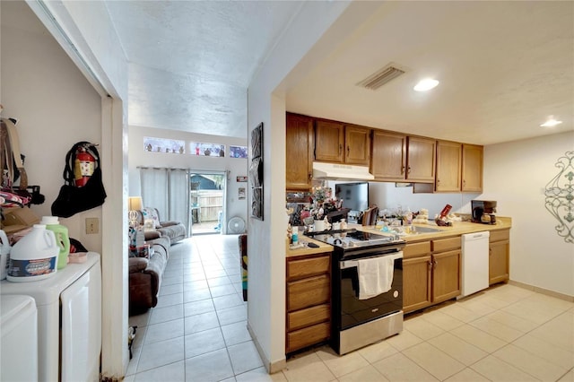 2826 NE 7th St, Ocala, FL 34470 - kitchen with washing machine and clothes dryer, stainless steel range with electric cooktop, white dishwasher, under cabinet range hood, and light countertops