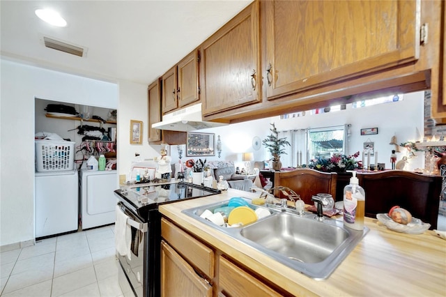 2826 NE 7th St, Ocala, FL 34470 - kitchen with washer and dryer, black electric range oven, light countertops, light tile patterned flooring, and under cabinet range hood