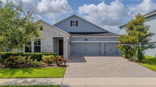 4632 Egg Harbor Dr, Kissimmee, FL 34746 - traditional-style house featuring decorative driveway, a garage, stone siding, and stucco siding
