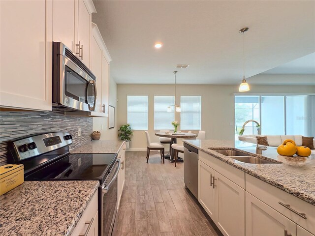 4632 Egg Harbor Dr, Kissimmee, FL 34746 - kitchen featuring appliances with stainless steel finishes, a sink, light wood finished floors, tasteful backsplash, and white cabinets
