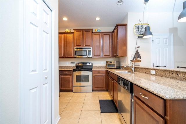 14231 Desert Haven St Unit Ge, Windermere, FL 34786 - kitchen featuring appliances with stainless steel finishes, a sink, a peninsula, light tile patterned flooring, and light stone countertops