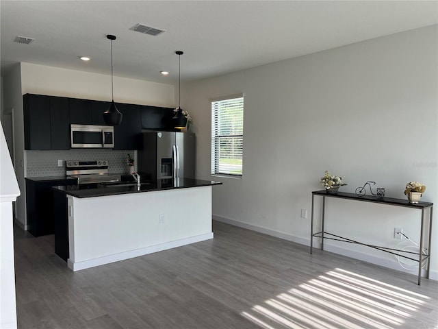 3301 Tranquil Trl, Kissimmee, FL 34747 - kitchen with appliances with stainless steel finishes, dark cabinetry, recessed lighting, wood finished floors, and tasteful backsplash