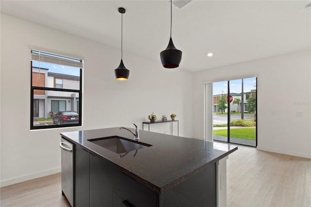 3301 Tranquil Trl, Kissimmee, FL 34747 - kitchen with stainless steel dishwasher, light wood-style floors, hanging light fixtures, a kitchen island with sink, and recessed lighting