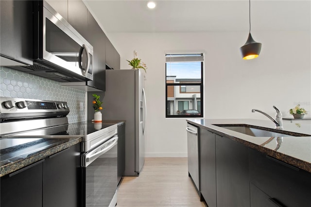 3301 Tranquil Trl, Kissimmee, FL 34747 - kitchen featuring stainless steel appliances, dark cabinetry, backsplash, decorative light fixtures, and light wood-style floors