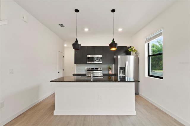 3301 Tranquil Trl, Kissimmee, FL 34747 - kitchen with stainless steel appliances, light wood-style flooring, backsplash, dark cabinets, and recessed lighting