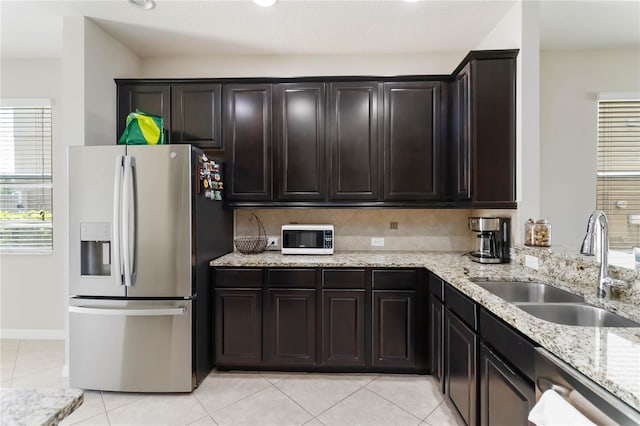 5217 Creekside Park Ave, Orlando, FL 32811 - kitchen with stainless steel appliances, a sink, light tile patterned flooring, and light stone counters