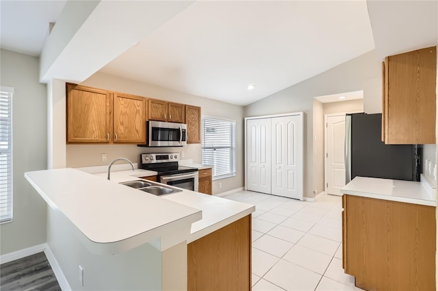 4305 Balmoral Ct, Wesley Chapel, FL 33543 - kitchen featuring appliances with stainless steel finishes, baseboards, light countertops, brown cabinets, and a peninsula