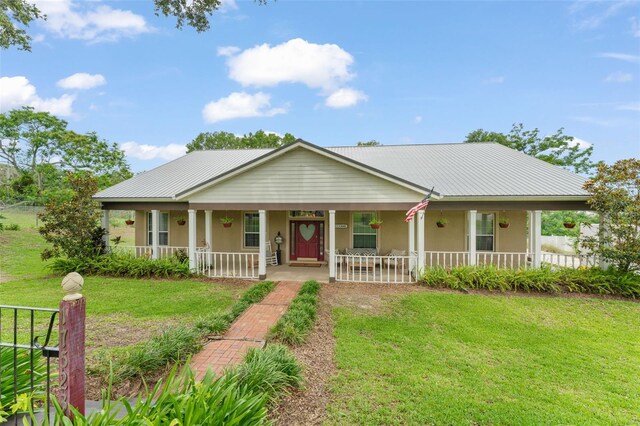17523 Doris St, Montverde, FL 34756 - farmhouse inspired home featuring covered porch, stucco siding, a front yard, and metal roof