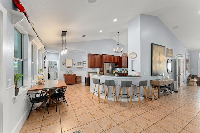 17523 Doris St, Montverde, FL 34756 - kitchen with stainless steel appliances, light tile patterned flooring, a kitchen bar, a chandelier, and high vaulted ceiling