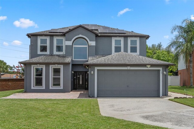 470 Regal Downs Cir, Winter Garden, FL 34787 - traditional-style house featuring driveway, stucco siding, an attached garage, and roof mounted solar panels