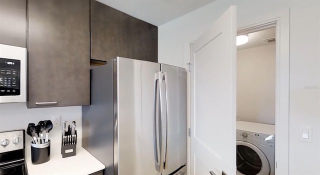 14501 Grove Resort Ave Unit 2440, Winter Garden, FL 34787 - kitchen featuring washer / dryer, freestanding refrigerator, white microwave, light countertops, and dark brown cabinets