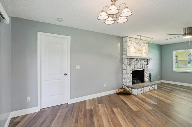 2704 Yule Tree Dr, Edgewater, FL 32141 - unfurnished living room featuring wood finished floors, a stone fireplace, ceiling fan, a chandelier, and a textured ceiling