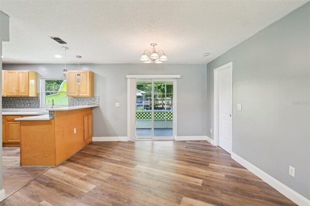 2704 Yule Tree Dr, Edgewater, FL 32141 - kitchen with light brown cabinetry, decorative backsplash, light wood-type flooring, and a chandelier