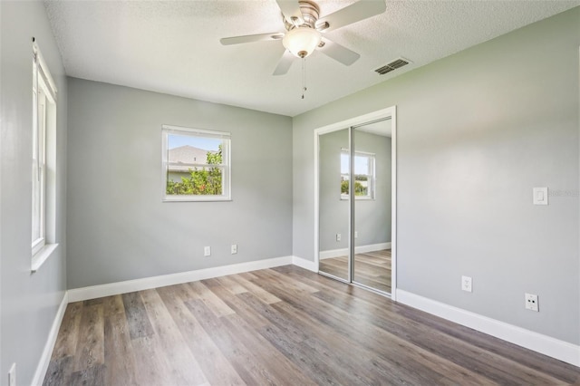 2704 Yule Tree Dr, Edgewater, FL 32141 - unfurnished bedroom with multiple windows, a closet, wood finished floors, baseboards, and a textured ceiling