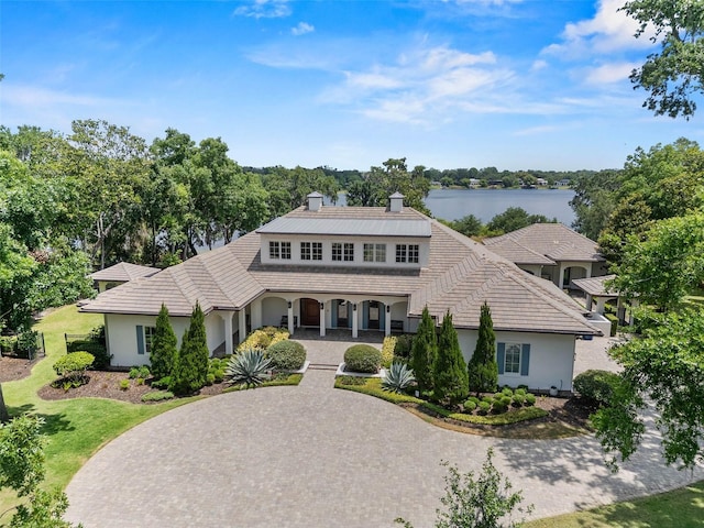 1112 Preserve Point Dr, Winter Park, FL 32789 - view of front of property with stucco siding, covered porch, a front yard, a water view, and a chimney