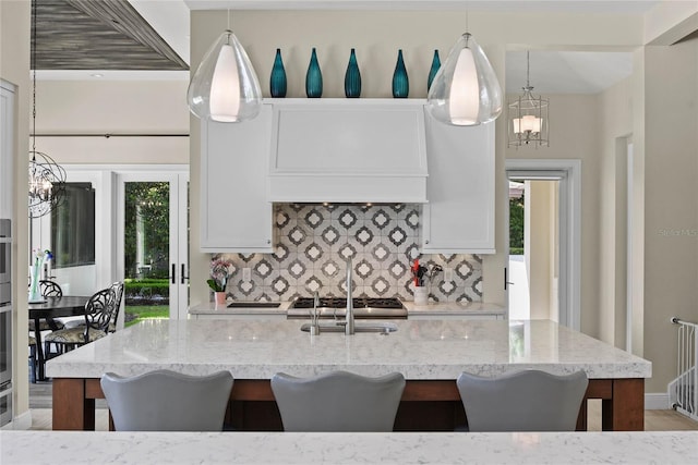 1112 Preserve Point Dr, Winter Park, FL 32789 - kitchen featuring a chandelier, decorative backsplash, a kitchen bar, and light stone countertops
