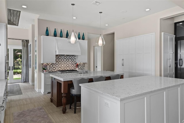 1112 Preserve Point Dr, Winter Park, FL 32789 - kitchen featuring a kitchen island with sink, backsplash, custom range hood, a breakfast bar, and recessed lighting
