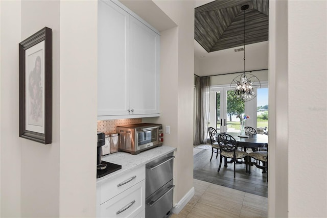 1112 Preserve Point Dr, Winter Park, FL 32789 - kitchen featuring white cabinetry, a chandelier, stainless steel dishwasher, baseboards, and pendant lighting
