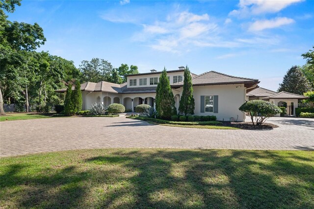 1112 Preserve Point Dr, Winter Park, FL 32789 - view of front of house with stucco siding, a front yard, and curved driveway