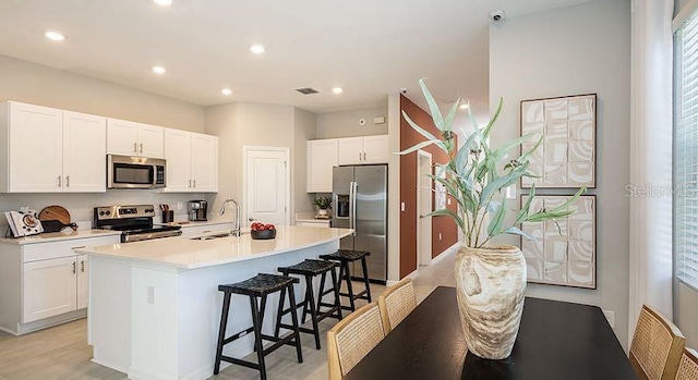 130 River Front Way, Edgewater, FL 32141 - kitchen with appliances with stainless steel finishes, a breakfast bar area, white cabinetry, an island with sink, and recessed lighting