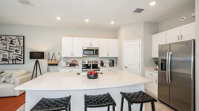 130 River Front Way, Edgewater, FL 32141 - kitchen featuring appliances with stainless steel finishes, white cabinetry, light countertops, a kitchen bar, and recessed lighting