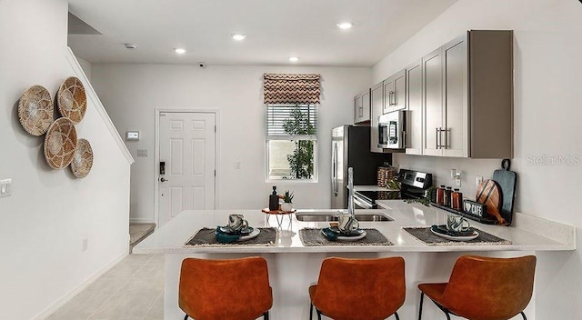 3064 Skyline Loop, Kissimmee, FL 34758 - kitchen with stainless steel appliances, a sink, a peninsula, a kitchen bar, and gray cabinets