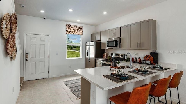 3064 Skyline Loop, Kissimmee, FL 34758 - kitchen with appliances with stainless steel finishes, gray cabinets, light countertops, a breakfast bar, and a peninsula