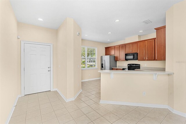 12963 Garridan Ave, Windermere, FL 34786 - kitchen with black appliances, light countertops, a peninsula, a breakfast bar, and light tile patterned flooring