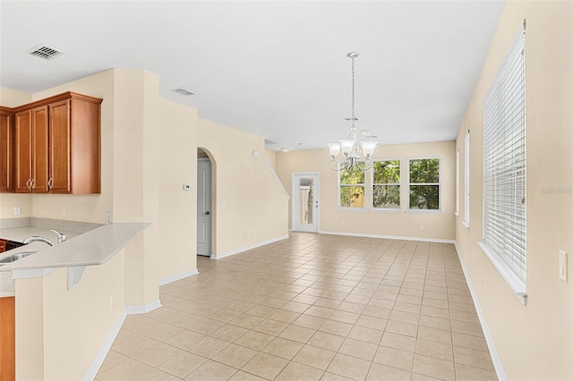 12963 Garridan Ave, Windermere, FL 34786 - unfurnished living room with a chandelier, arched walkways, light tile patterned floors, a sink, and baseboards