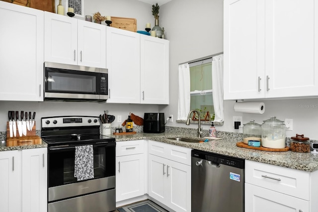 7616 Simms Ave, Orlando, FL 32812 - kitchen featuring stainless steel appliances, a sink, white cabinetry, and light stone countertops