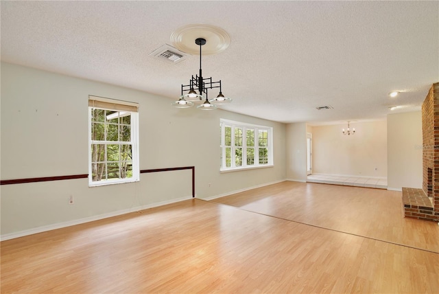 4802 Anton Ave, Apopka, FL 32712 - unfurnished living room with a chandelier, a textured ceiling, light wood-style flooring, and baseboards