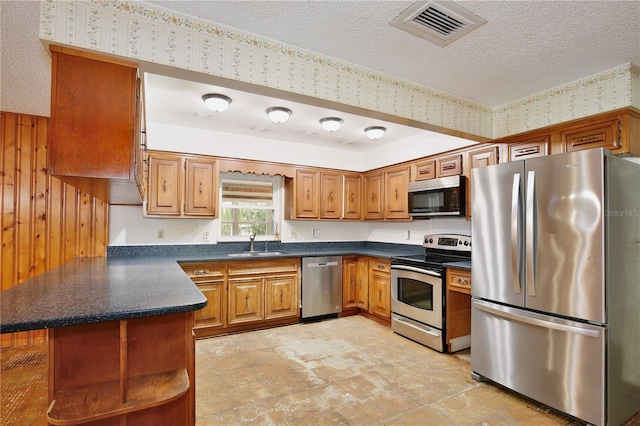 4802 Anton Ave, Apopka, FL 32712 - kitchen with appliances with stainless steel finishes, a sink, a peninsula, brown cabinets, and dark countertops