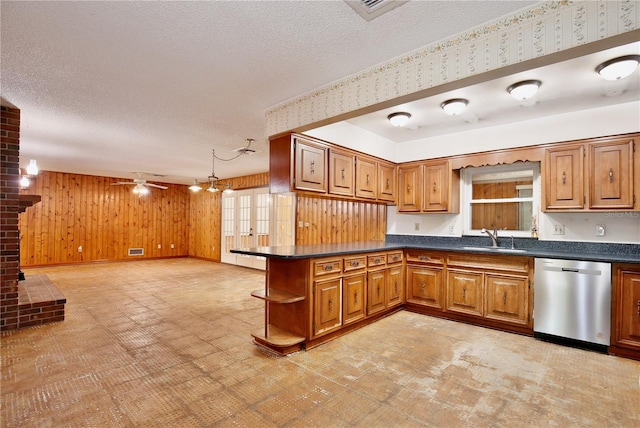 4802 Anton Ave, Apopka, FL 32712 - kitchen with stainless steel dishwasher, dark countertops, a sink, brown cabinetry, and wood walls