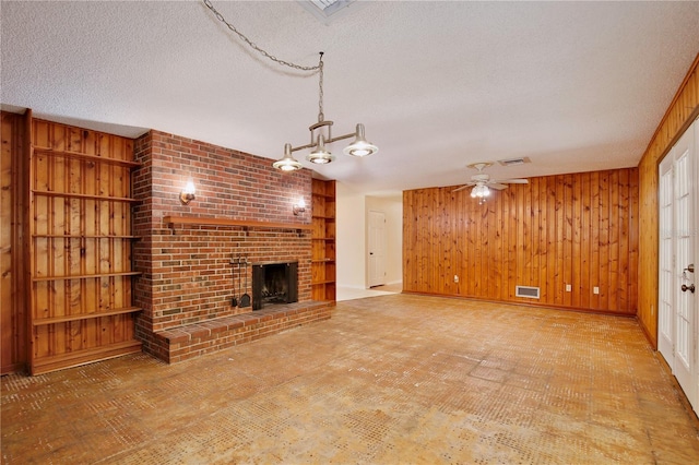 4802 Anton Ave, Apopka, FL 32712 - unfurnished living room featuring wood walls, a fireplace, a ceiling fan, a textured ceiling, and a chandelier