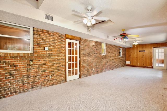 4802 Anton Ave, Apopka, FL 32712 - unfurnished living room featuring a ceiling fan, brick wall, wood walls, carpet flooring, and a textured ceiling