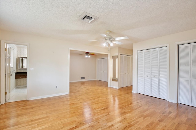 4802 Anton Ave, Apopka, FL 32712 - unfurnished bedroom featuring two closets, light wood-type flooring, a textured ceiling, baseboards, and ensuite bath