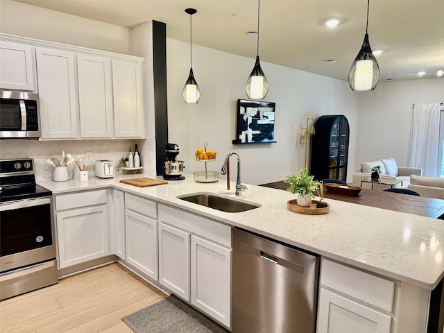1900 Erudite Way, Winter Park, FL 32792 - kitchen featuring appliances with stainless steel finishes, a sink, white cabinetry, light wood-style floors, and open floor plan